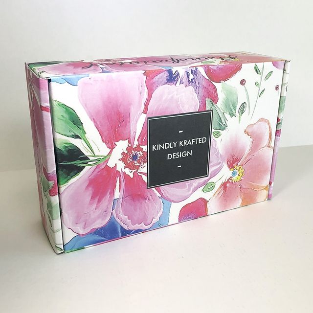 Floral subscription box with pink lilies and black brand label