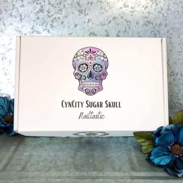White box with mandala-style logo and purple flower